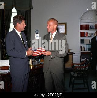 Visita dell'astronauta John Herschel Glenn, Jr. Il presidente John F. Kennedy riceve un dono di una bandiera americana dall'astronauta tenente colonnello John H. Glenn, Jr. (A destra); il Lt. Colon ha portato la bandiera nella sua tuta spaziale durante il suo volo orbitale a bordo del Mercury-Atlas 6, noto anche come amicizia 7. Assistente speciale del presidente, Kenneth P. Ou0027Donnell, spicca parzialmente fuori quadro sullo sfondo. Ufficio ovale, Casa Bianca, Washington, D.C. Foto Stock