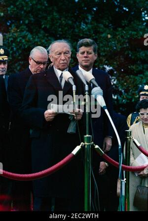 Cerimonie di arrivo per Konrad Adenauer, Cancelliere della Germania Occidentale, 10:45. Il presidente John F. Kennedy guarda come il Cancelliere della Germania occidentale, il Dr. Konrad Adenauer, fa le sue osservazioni durante le cerimonie di arrivo in suo onore. Anche nella foto: Presidente dei Capi di Stato, Generale Maxwell D. Taylor; Ambasciatore della Germania Ovest, Karl Heinrich Knappstein; Assistente Capo dei servizi linguistici del Dipartimento di Stato, interprete Nora Lejins; militare Aide al Presidente, Generale Chester V. Clifton. South Lawn, Casa Bianca, Washington, D.C. Foto Stock
