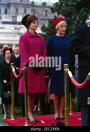 Cerimonie di arrivo per Konrad Adenauer, Cancelliere della Germania Occidentale, 10:45. First Lady Jacqueline Kennedy partecipa alle cerimonie di arrivo in onore del Cancelliere della Germania occidentale, Dr. Konrad Adenauer. Libeth Werhahn, figlia del Cancelliere Adenauer, si trova a destra sulla piattaforma di revisione; Virginia Rusk, moglie del Segretario di Stato degli Stati Uniti, Dean Rusk, si trova a sinistra sotto la piattaforma. South Lawn, Casa Bianca, Washington, D.C. Foto Stock