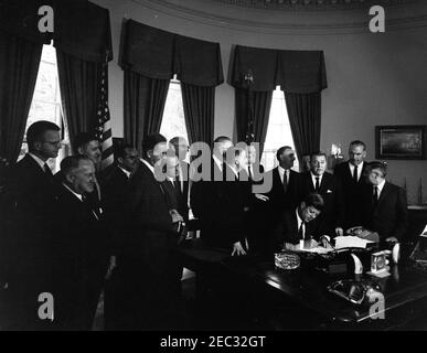 205 Legge pubblica 87-447, Legge sulla Televisione educativa, 12:00 PM. Il presidente John F. Kennedy (seduto) firma la legge sulla televisione educativa. Standing (L-R): Tre uomini non identificati; Presidente della Federal Communications Commission (FCC), Newton Minow (sul retro); Senatore Clifford P. Case (New Jersey); Congressman John E. Moss (California); Unidentified; Senatore Norris Cotton del New Hampshire (volto oscurato); Congressman Oren Harris (Arkansas); Congressman Hale Boggs (Louisiana); Segretario della Sanità, Istruzione e Welfare, Abraham Ribicoff; avvocato, Leonard H. Marks (in retrocedenza); Senatore Foto Stock