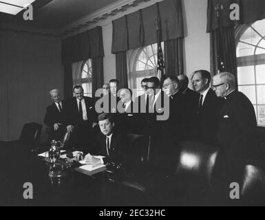 Firma della proclamazione - Voluntary Overseas Aid Week, 11:30. Il presidente John F. Kennedy (seduto) fa un commento alla firma della proclamazione che designa la settimana del 9 aprile 1962 come settimana volontaria degli aiuti esteri. I leader delle organizzazioni umanitarie e religiose americane guardano avanti. In piedi, (L-R): Non identificato; Richard W. Reuter, Direttore Esecutivo DELL'ASSISTENZA; Fowler Hamilton, Amministratore dell'Agenzia per lo sviluppo Internazionale (a ritroso); Dr. Franklin Clark Fry, Presidente del Lutheran World Relief; Joseph Meyerhoff, Presidente Generale dell'appello ebraico Unito; Segretario di Agricultur Foto Stock