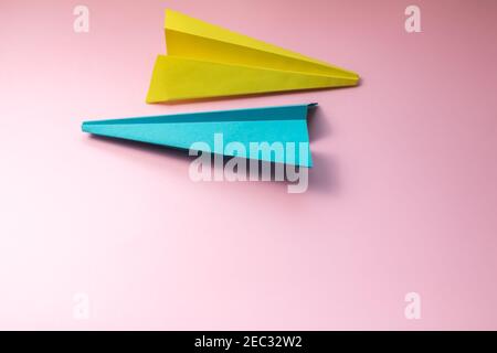 Due piani di carta volanti su sfondo di carta rosa. Aereo simbolo di viaggio e turismo Foto Stock