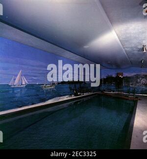 Installazione di altoparlanti in piscina Casa Bianca. Un uomo non identificato si trova su una scala durante l'installazione di altoparlanti nella piscina della Casa Bianca, Washington D.C. le pareti presentano un murale dipinto da Bernard Lamotte. Foto Stock