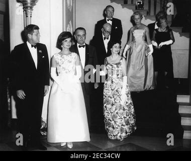 Ricevimento congressuale alla Casa Bianca, 21:30. Il presidente John F. Kennedy, la First Lady Jacqueline Kennedy, e altri frequentano un ricevimento congressuale alla Casa Bianca. Prima fila (L-R): Presidente Kennedy, Sig.ra Kennedy, Vice Presidente Lyndon B. Johnson e Lady Bird Johnson. Scendendo le scale (L-R) Senatore Carl Hayden (Arizona); Senatore Hubert H. Humphrey (Minnesota); Muriel Humphrey, moglie del senatore Humphrey; Louella Dirksen, moglie del senatore Everett M. Dirksen (Illinois); e Senatore Dirksen (per lo più nascosto). Grand Staircase, ingresso Hall, Casa Bianca, Washington, D.C. Foto Stock