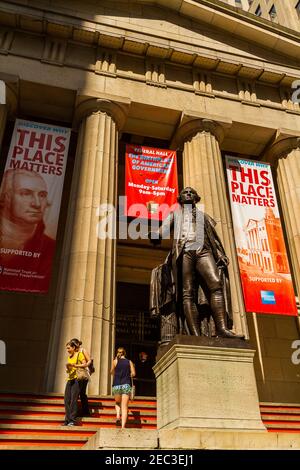 La statua di George Washington di fronte al Federal Hall in Wall Street nel quartiere finanziario con il edificio sul retro e le persone sul Foto Stock