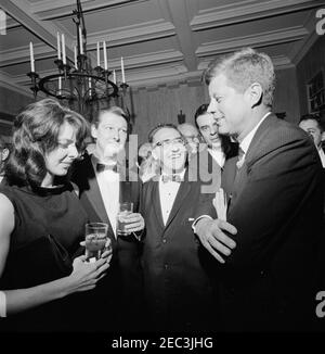 Viaggio a New York: Ricevimento, residenza Arthur Krim. Il presidente John F. Kennedy visita con i comici Elaine May e Mike Nichols (entrambi a sinistra), durante un ricevimento serale presso la residenza di Arthur B. Krim e il Dr. Mathilde Krim a New York City, New York. Il compositore Richard Adler si trova a destra (parzialmente nascosto). Foto Stock