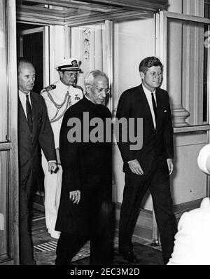 Cerimonia di arrivo del Dr. Sarvepalli Radhakrishnan, Presidente dell'India, 11:40. Il presidente John F. Kennedy (destra) e il presidente dell'India, il dottor Sarvepalli Radhakrishnan (centro), partono dalla Casa Bianca per Blair House, dopo l'arrivo del presidente Radhakrishnanu2019. Camminando dietro (L-R): Capo DEL protocollo DEGLI STATI UNITI, duca di Angier Biddle; Aide navale al presidente Kennedy, capitano Tazewell Shepard. Portico Nord, Casa Bianca, Washington, D.C. Foto Stock