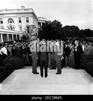 Visita dei cadetti stranieri di pattuglia aerea civile, 9:35. Il presidente John F. Kennedy (a sinistra) e il senatore Hubert Humphrey del Minnesota (al centro, di nuovo alla telecamera) parlano con due ufficiali militari non identificati, durante una visita con un gruppo di cadetti di pattuglia aerea civile stranieri. Rose Garden, Casa Bianca, Washington, D.C. Foto Stock