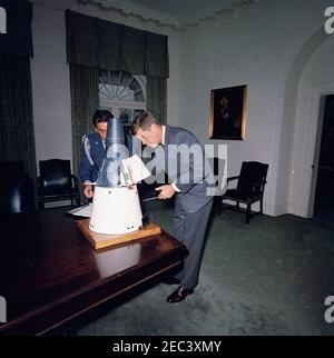 Il presidente Kennedy con una capsula Gemini modello. Il presidente John F. Kennedy vede un modello in scala di una capsula Gemini nella stanza del gabinetto della Casa Bianca, Washington, D.C.; Il modello è stato dato al presidente Kennedy come regalo di Natale dal personale della McDonnell Aircraft Corporation, dopo la visita del presidente 2019 allo stabilimento di McDonnellu2019s St. Louis il 12 settembre 1962. Air Force Aide al presidente, Brigadier General Godfrey T. McHugh, si trova dietro la capsula. [Vedi anche MO 63.1922a-c, u0022Scale Model of the Gemini Spacecraftu0022] Foto Stock