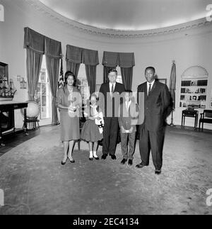 Visita di Myrlie Evers, vedova di Medgar Evers, e la famiglia. Il presidente John F. Kennedy (centro) visita con Myrlie Evers (all'estrema sinistra), vedova del leader dei diritti civili, Medgar Evers. Anche nella foto: Reena e Darrell Evers, figli di Medgar e Myrlie; Charles Evers (a destra), fratello di Medgar. Ufficio ovale, Casa Bianca, Washington, D.C. Foto Stock