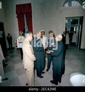 Cerimonia di arrivo del Dr. Sarvepalli Radhakrishnan, Presidente dell'India, 11:40. Il presidente John F. Kennedy e altri si recheranno con il presidente dell'India, il dottor Sarvepalli Radhakrishnan (a destra), dopo il suo arrivo alla Casa Bianca. Il generale Maxwell D. Taylor e il Segretario di Stato, Dean Rusk, si trovano a sinistra; l'Aide navale del presidente Kennedy, il capitano Tazewell Shepard, si trova al centro dello sfondo. Altri non sono identificati. Ingresso Hall, Casa Bianca, Washington, D.C. Foto Stock