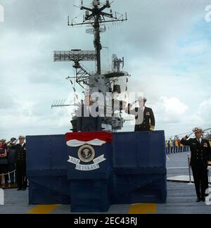Viaggio negli Stati occidentali: Visita alla Pacific Fleet, presidente Kennedy a bordo della USS Oriskany, 16:00. Il presidente John F. Kennedy (centro) e il comandante in capo della flotta del Pacifico (CINCPACFLT), l'ammiraglio John H. Sides (destra, saluto), Sali sulla piattaforma di revisione a bordo del ponte di volo della portaerei USS Oriskany (CVA-34) mentre le navi della task force eseguono un saluto da 21 cannoni in onore della visita del presidente Kennedyu0027s alla US Pacific Fleet, in mare al largo della costa di San Diego, California. Capo delle operazioni Navali, l'ammiraglio George W. Anderson Jr. (Saluting), si trova a sinistra di platfo Foto Stock
