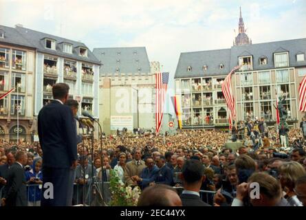 Viaggio in Europa: Germania, Francoforte: Il presidente Kennedy dà il discorso in Piazza Roemerberg, 16:00 PM. Il presidente John F. Kennedy (a sinistra, di ritorno alla telecamera) si prepara a consegnare un discorso a una folla riunita a Ru00f6merberg Square a Francoforte sul meno, Germania occidentale (Repubblica federale); il direttore della radio nel settore americano (RIAS) a Berlino e il traduttore per il presidente Kennedy, Robert Lochner, si trova ai microfoni. Foto Stock
