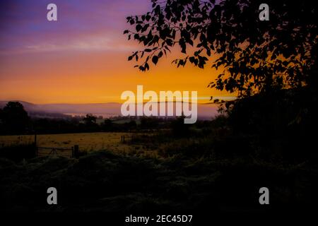 Fiery alba su campi che si affacciano sul lago Ullswater Foto Stock