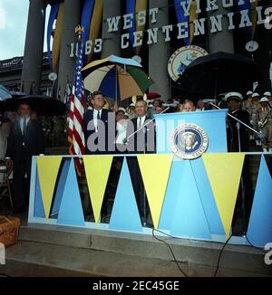 Viaggio a West Virginia: Indirizzo alla celebrazione del Centennial della West Virginia, state Capitol Building, Charleston, 11:30. Il presidente John F. Kennedy (a sinistra) partecipa a una celebrazione commemorativa del centenario della West Virginia sui gradini del Campidoglio di Stato a Charleston, West Virginia. Governatore della Virginia Occidentale, William W. Barron, si trova a sinistra del leggio. Anche nella foto: Il senatore Robert C. Byrd della Virginia Occidentale (dietro il Governatore Barron); il rappresentante Harley O. staggers della Virginia Occidentale (dietro il leggio, in background); gli agenti del Servizio Segreto della Casa Bianca, Ken Giannoules e Ron Pontius. [PH Foto Stock