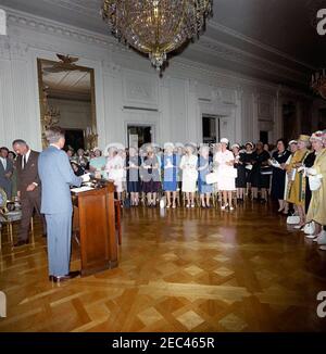 Incontro con i rappresentanti delle organizzazioni womenu0027s per discutere i diritti civili, 16:15. Il presidente John F. Kennedy (al leggio) si prepara a rivolgersi ad un gruppo di ufficiali e rappresentanti delle organizzazioni femminili 2019 in materia di diritti civili; i partecipanti applaudono al presidente prima delle sue osservazioni di apertura. Camminando verso le sedie a sinistra sono il Vice Presidente Lyndon B. Johnson e il Procuratore Generale Robert F. Kennedy. Camera Est, Casa Bianca, Washington, D.C. Foto Stock