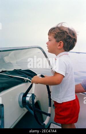 Weekend del Labor Day al porto di Hyannis: John F. Kennedy, Jr. (JFK Jr.), al volante del motoscafo. John F. Kennedy, Jr., si trova al volante di un motoscafo durante il fine settimana del Labor Day a Hyannis Port, Massachusetts. Foto Stock