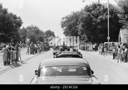 Viaggio negli stati occidentali: Pueblo, Colorado, 12:50. Il presidente John F. Kennedy (in auto) ondeggia da un convertibile mentre la sua motocicletta viaggia attraverso Pueblo, Colorado. Le folle costeggiano la strada. Foto Stock