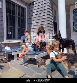 Viaggio a Hyannis Port u2013 Squaw Island, 1963-08-14. Il presidente John F. Kennedy, First Lady Jacqueline Kennedy, e i loro figli, Caroline Kennedy e John F. Kennedy, Jr., giocano con i loro cani, Shannon, Wolf, White Tips, Blackie, Clipper, e Charlie, a Brambletyde a Squaw Island, Hyannis Port, Massachusetts. Foto Stock