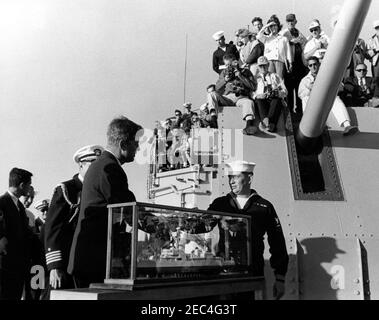 Il presidente Kennedy si accuda alla prima gara di Coppa Americau0027s. Il presidente John F. Kennedy riceve un modello di nave di cacciatorpediniere, la USS Joseph P. Kennedy Jr., in dono dall'equipaggio della Joseph P. Kennedy Jr., mentre partecipa alla prima gara della Coppa Americau0027s 1962 a bordo del cacciatorpediniere. Naval Aide al presidente, Captain Tazewell Shepard, si trova dietro il presidente Kennedy (parzialmente nascosto). Newport, Rhode Island. Foto Stock