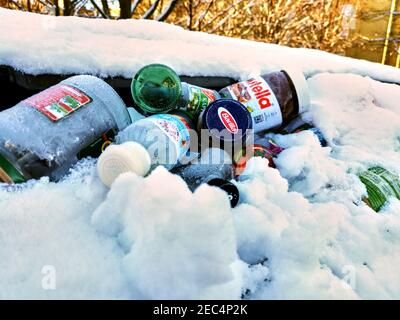 Berlino, Germania - 31 gennaio 2021: Rifiuti di vetro in un contenitore di riciclaggio coperto di neve di un'azienda di rifiuti di Berlino. Foto Stock