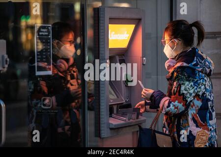 Donna che preleva denaro da un distributore di contanti della banca Santander a Londra, Inghilterra, Regno Unito Foto Stock