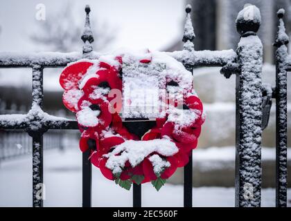 Giorno della memoria corona di fiori di papavero rosso attaccata a ringhiere nere Domenica 11 novembre nella scena invernale della neve Foto Stock