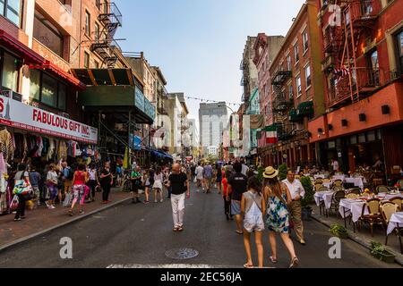 La vista di Mulberry Street a Little Italy, Manhattan con i turisti che passeggiano per i ristoranti e i negozi italiani lungo la strada Foto Stock