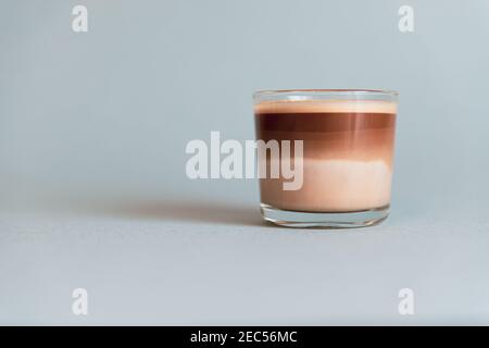 Mini tazza di caffè multistrato in una tazza di vetro su sfondo grigio Foto Stock