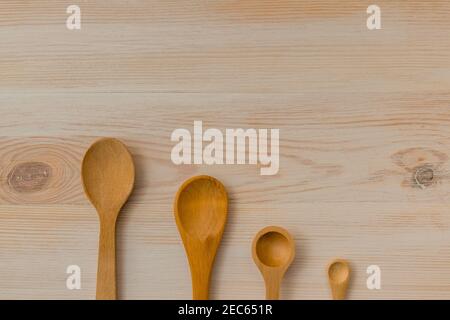 Cucchiai di legno su superficie di legno. Vari utensili in legno di diverse dimensioni in stile vintage. Sfondo per lo spazio di copia. Foto Stock