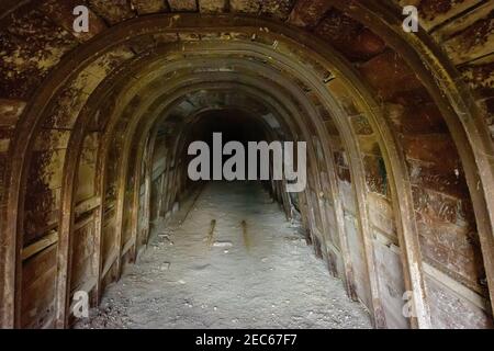 Tunnel sotterraneo scuro con pareti in legno in miniera abbandonata Foto Stock