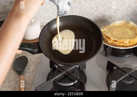 Persona che cucinano le frittelle sottili sulla padella in cucina Foto Stock