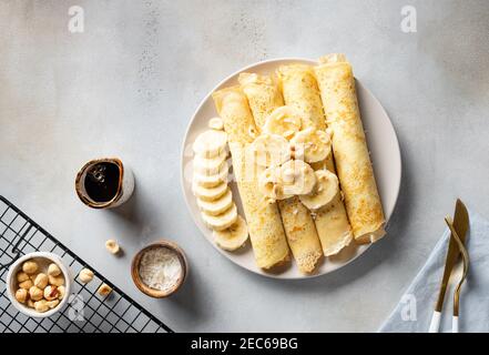 frittelle arrotolate, crepes servite con banana, noci, cocco Foto Stock