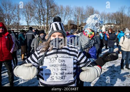 Rosenheim, Germania. 13 Feb 2021. Un dimostratore indossa un vestito di condanna con un segno che indica "sono innocente - chiedo la mia libertà indietro. Ora', mentre una donna che indossa un cappello di alluminio può essere visto sullo sfondo. Credit: Attias Balk/dpa/Alamy Live News Foto Stock