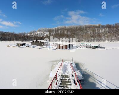 13 febbraio 2021, Sassonia-Anhalt, Wendefurth: Vista della stazione di noleggio barche innevate sul serbatoio vicino a Wendefurt. La stazione di noleggio barche si trova come un'isola sul lago artificiale ghiacciato. Foto: Mathias Bein/dpa-Zentralbild/dpa Foto Stock