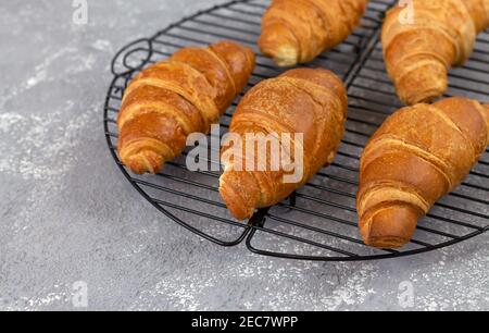 Croissant appena sfornati su griglia di raffreddamento. Tradizionale concetto di colazione francese Foto Stock