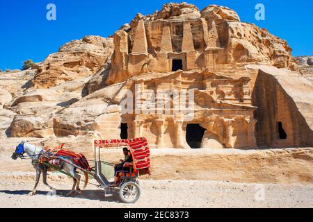 Carrozza a cavallo beduina di fronte alle tombe di Djinn blocca antiche tombe di Petra in Giordania Foto Stock