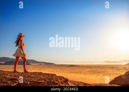Ragazza turista che guarda sulle sabbie rosse del deserto di Wadi Rum nel tempo del tramonto, Giordania Foto Stock