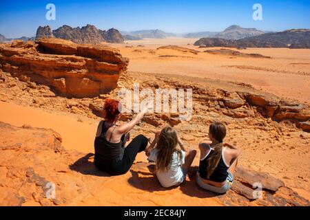 La famiglia si affaccia sulle sabbie rosse del deserto di Wadi Rum al tramonto, Giordania Foto Stock