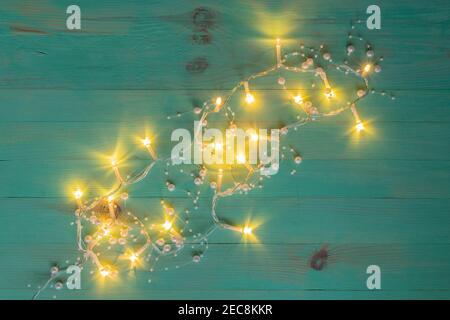 Decorazione delle luci di Natale su sfondo di tessitura di legno. Terreno luminoso su sfondo dipinto di verde d'epoca. Spazio di copia, vista dall'alto. Foto Stock