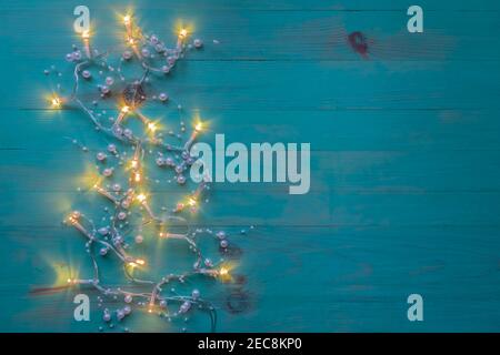 Decorazione luci di Natale su legno texture sfondo blu. Terreno luminoso su sfondo dipinto d'epoca. Spazio per il testo, vista dall'alto. Foto Stock