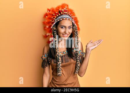 Giovane donna bruna che indossa costume indiano sorridendo allegro presentazione e puntando con palmo di mano guardando la fotocamera. Foto Stock