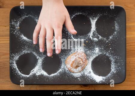 Mano del bambino che raggiunge l'ultimo cookie sul vassoio Foto Stock