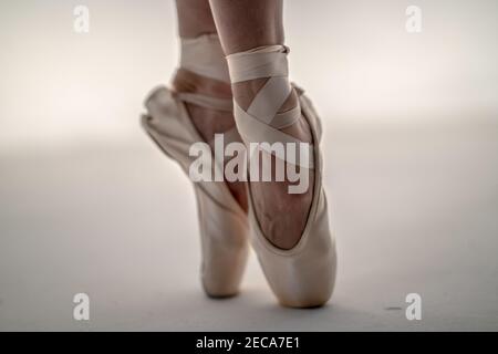 Primo piano dei piedi di una ballerina che indossano scarpe appuntite su un sfondo bianco Foto Stock