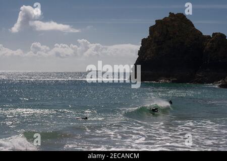 Un body boarder nel surf a Kynance Cove, Lizard Peninsula, Cornovaglia. Una nave portarinfuse all'orizzonte della distanza. Foto Stock