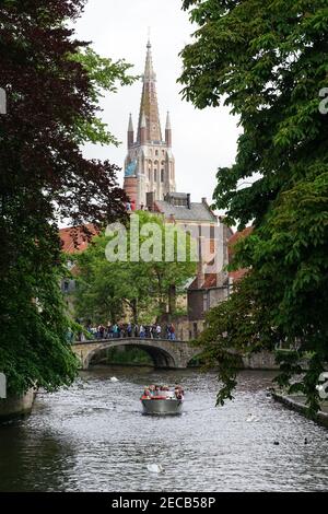 Turisti su un ponte sul canale Bakkersrei con la torre della Chiesa di nostra Signora sullo sfondo, Bruges, Belgio Foto Stock