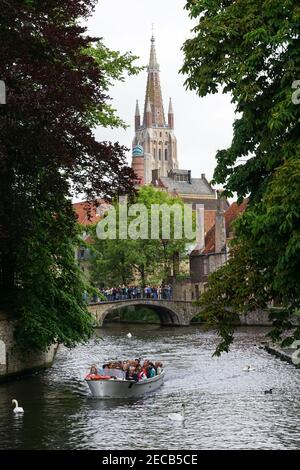 Turisti su un ponte sul canale Bakkersrei con la torre della Chiesa di nostra Signora sullo sfondo, Bruges, Belgio Foto Stock