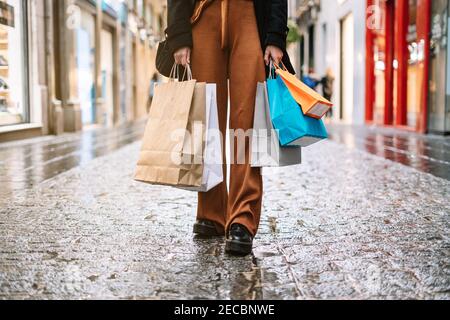 Donna irriconoscibile con maschera facciale e shopping colorato in strada. Foto Stock