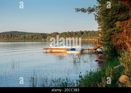 Estate sul lago cottage. Piccola barca a bordo di un molo in legno sul lago al tramonto. Canada Ontario Muskoka luogo di viaggio destinazione. Sport acquatici estivi Foto Stock