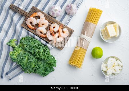 Ingredienti per pasta con frutti di mare. Gamberetti, spaghetti, parmigiano, ricotta, su fondo bianco, vista dall'alto in piano Foto Stock